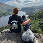Person with a dog on a rocky mountain top with a scenic view.