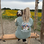 Person with a dog on a swing in a field of yellow flowers