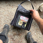 Person holding a black bag with dog-themed design on a concrete surface