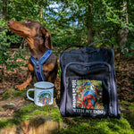 Dog sitting outdoors with a backpack and mug in front of a forest background