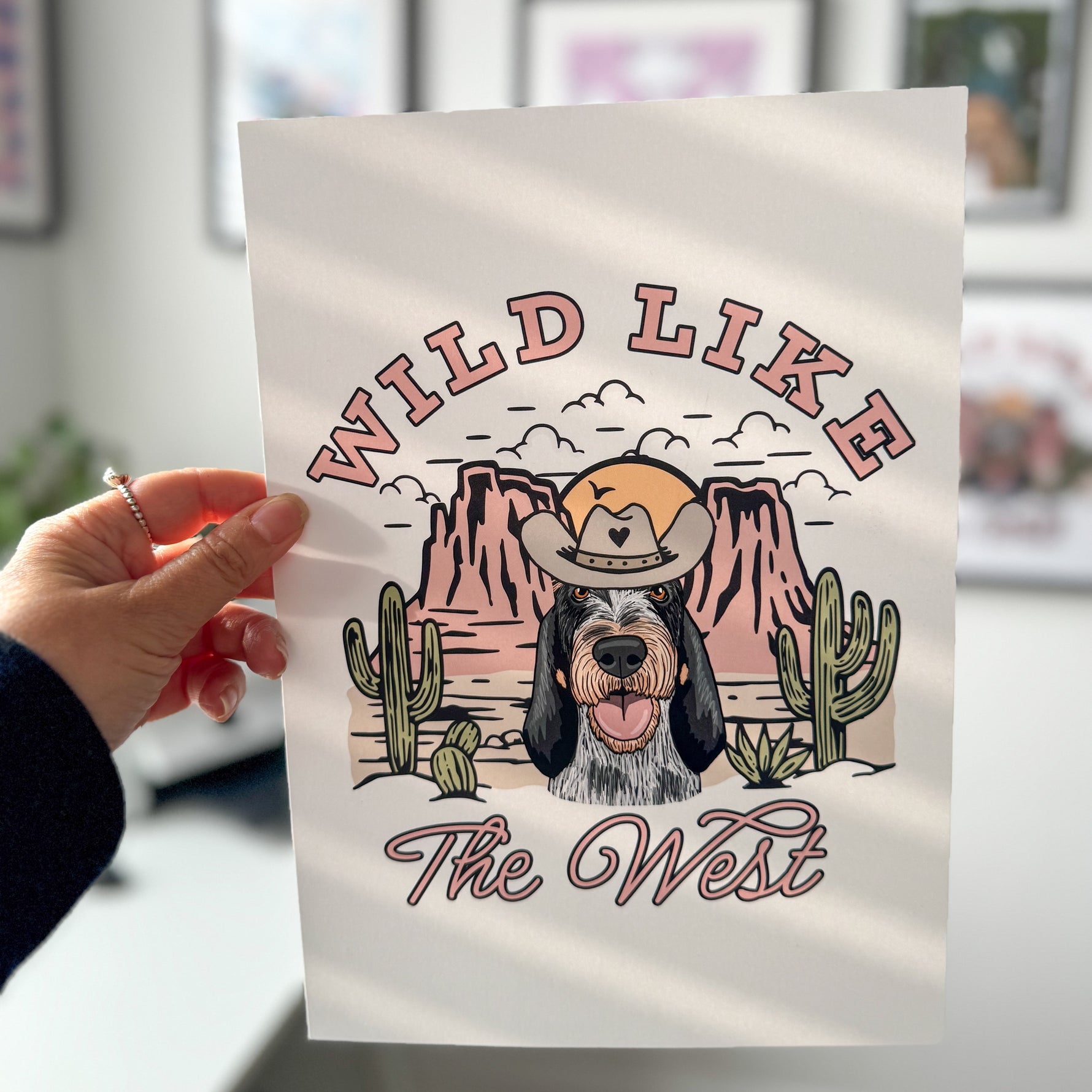 Person holding a tote bag with a dog graphic and 'Wild Like The West' text.