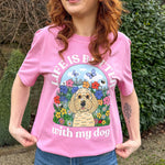 Person wearing a pink t-shirt with a dog illustration and text in an outdoor setting