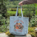 Tote bag with 'Wild Like The Wild' design held by a hand in a natural setting