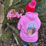 Woman wearing pink premium organic cotton hoodie with personalised dog illustration in wildflower meadow design, holding dog in Lake District