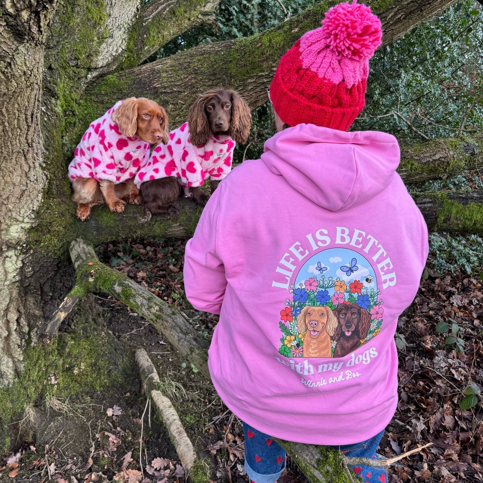 Woman wearing pink premium organic cotton hoodie with personalised dog illustration in wildflower meadow design, holding dog in Lake District