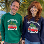 Two people wearing festive sweatshirts with a tree and car design outdoors.