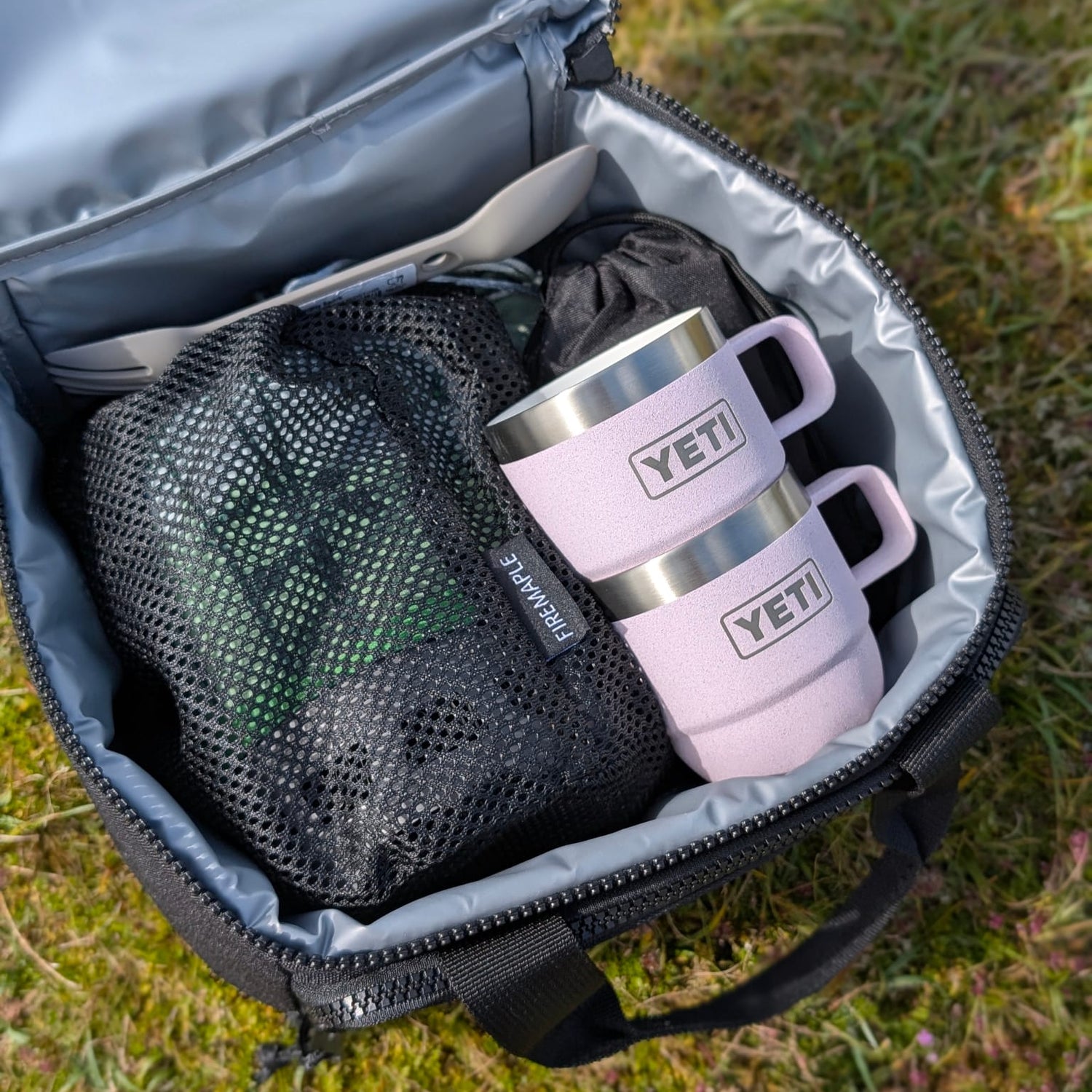 Pink YETI mug in an open bag on grass