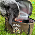 Dog looking into an open bag with 'Outside' branding on a grassy background