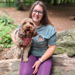 Woman sitting on a log with a dog in a forest setting