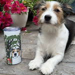 Dog sitting on a wooden deck with a tumbler featuring a dog illustration in the foreground.