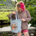 Person holding a tote bag with a design outdoors
