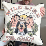Person holding a pillow with a dog illustration and 'Wild Like the West' text.