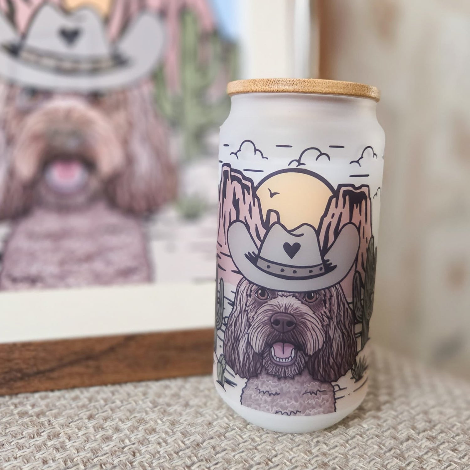 Can with a dog wearing a cowboy hat design, placed on a textured surface with a framed picture in the background.
