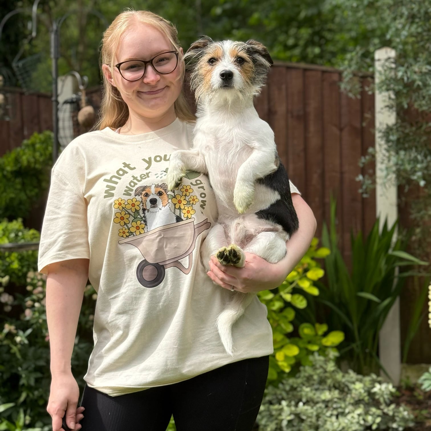 Woman holding a small dog in a garden setting