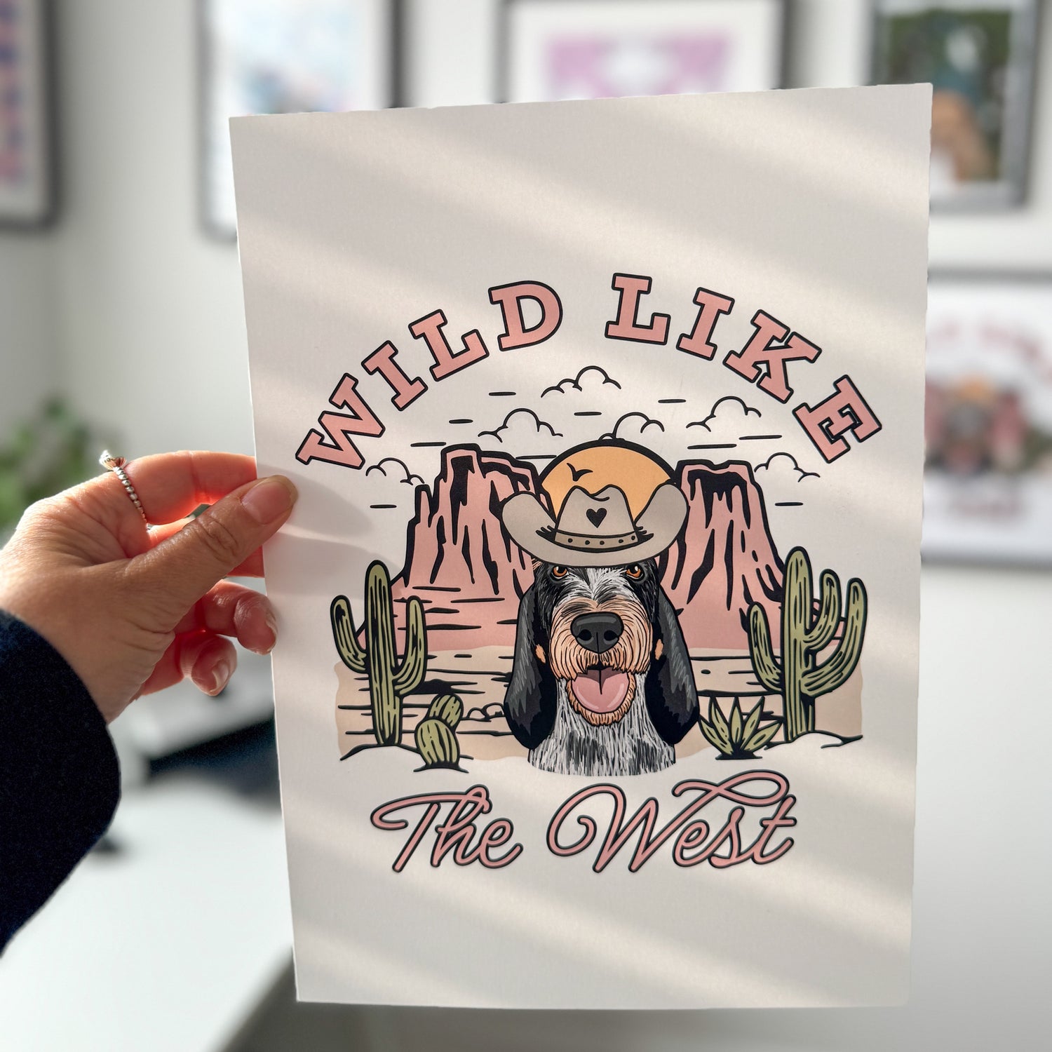 Person holding a tote bag with a dog graphic and 'Wild Like The West' text.