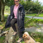 Woman sitting on a rock with a dog in a natural setting
