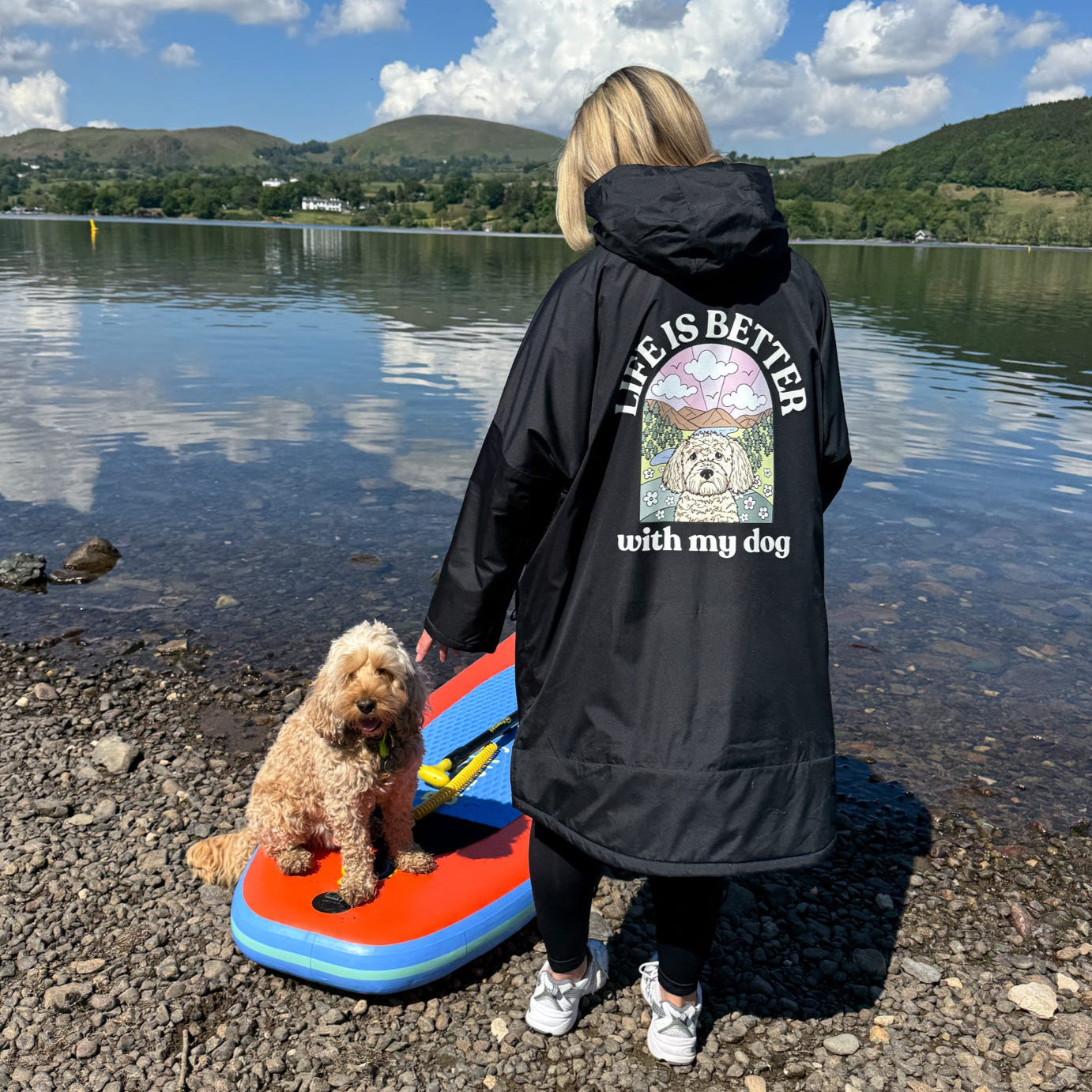 Person and dog by a lake with a scenic background