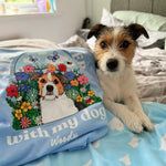 Dog lying on a bed next to a pillow with a floral design and text 'with my dog Woody'.