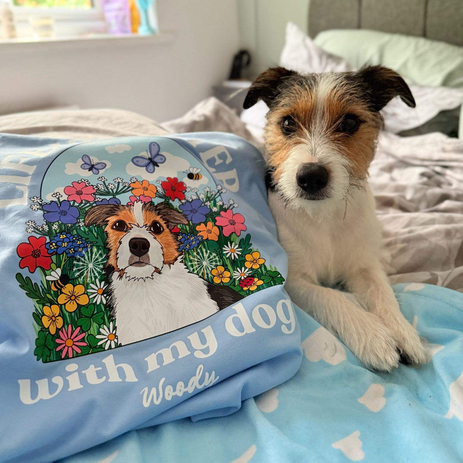 Dog lying on a bed next to a pillow with a floral design and text 'with my dog Woody'.