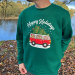 Person wearing a green sweatshirt with a Christmas-themed design outdoors.