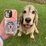 Dog sitting on grass next to a phone case with a dog illustration