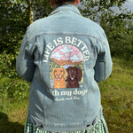 Person wearing a denim jacket with a dog-themed design outdoors.