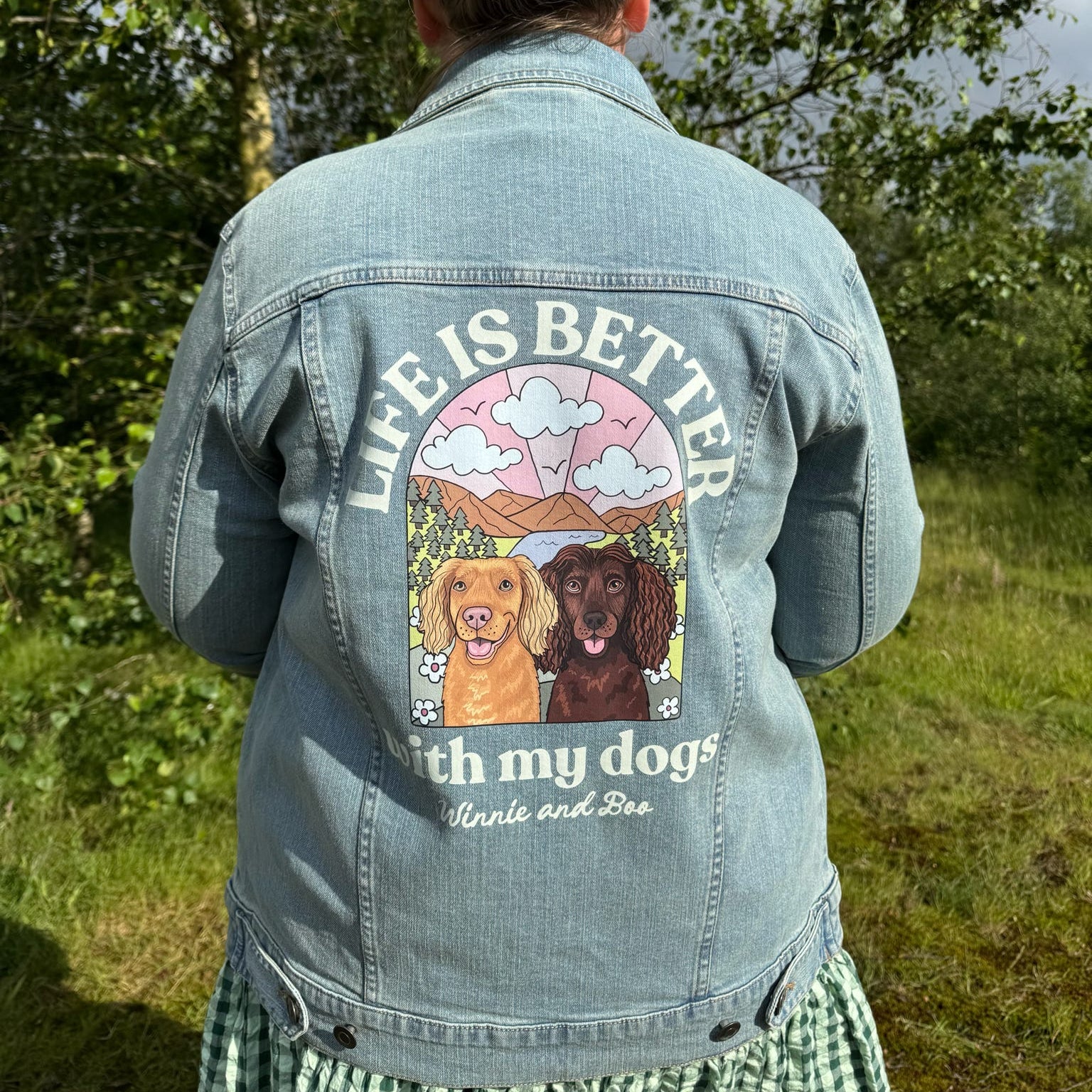 Person wearing a denim jacket with a dog-themed design outdoors.