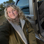 Person taking a selfie next to an open car door with a scenic background
