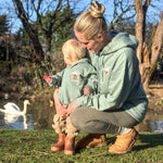 Woman and child in matching outfits by a pond with swans